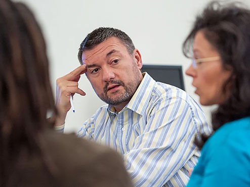 Three adult undergraduate students involved in a discussion over coursework.