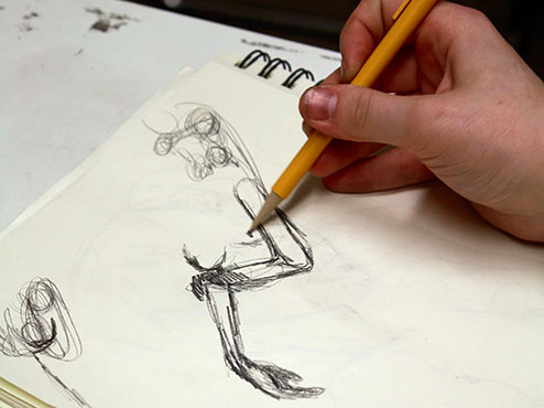 A student in a painting and drawing class does a pencil sketch of a human arm.