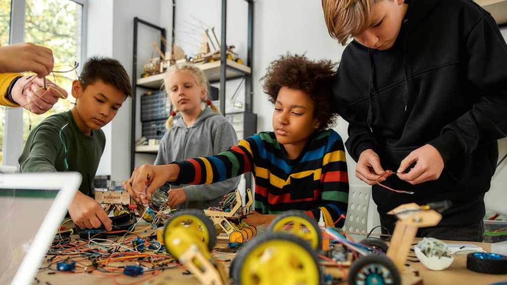 Young children are intent on their group work with robot parts at a CREATE Lab.