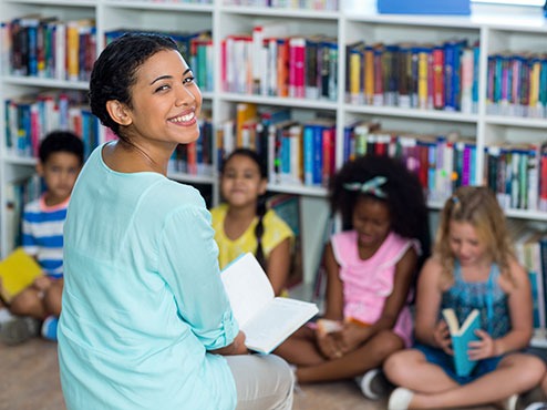 Early childhood special education teacher reaching to children sitting down