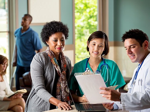 Healthcare manager overlooking paperwork with nurse and doctor staff