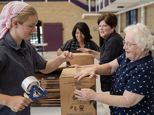 Four women pack boxes as part of mission work at Carlow.