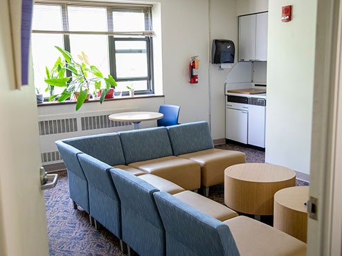 A common area in a Carlow dormitory has chairs and a small kitchen in the corner.