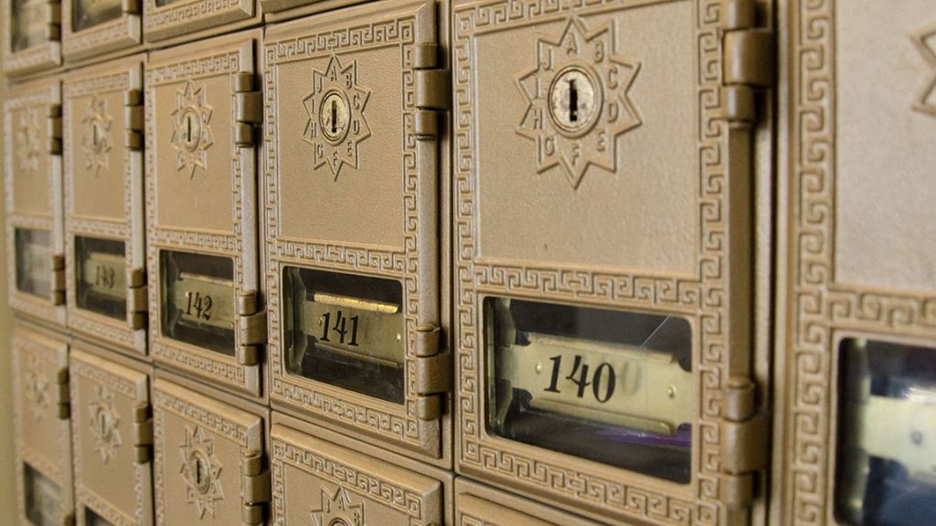 A bank of numbered student mailboxes with small windows.