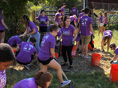 Students wearing purple Mercy Service Day T-shirts are hard at work on landscaping improvements.