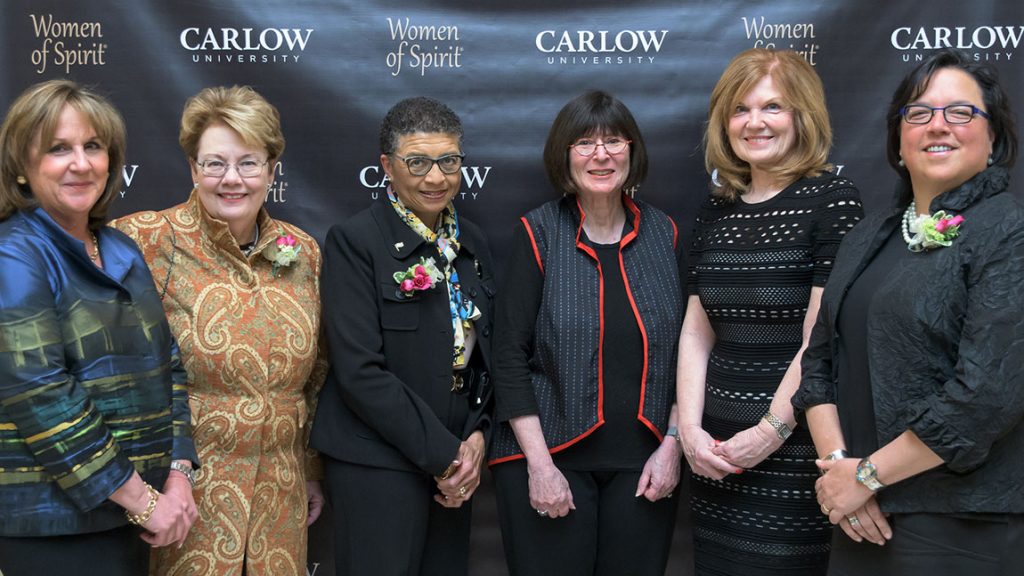 Past honorees of the Women of Spirit award stand in front of a banner reading Carlow University and Women of Spirit.
