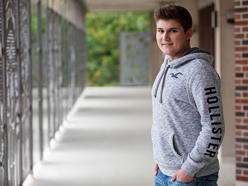 A male psychology major stands outside a building on the Carlow campus.