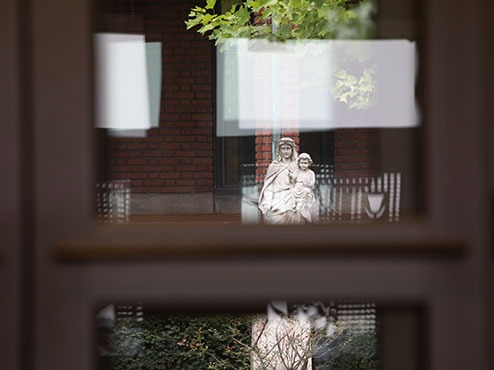 A Sisters of Mercy statue is seen through a top window and reflected below.