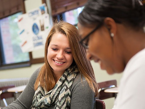 Two female undergraduate students work together in a classroom.