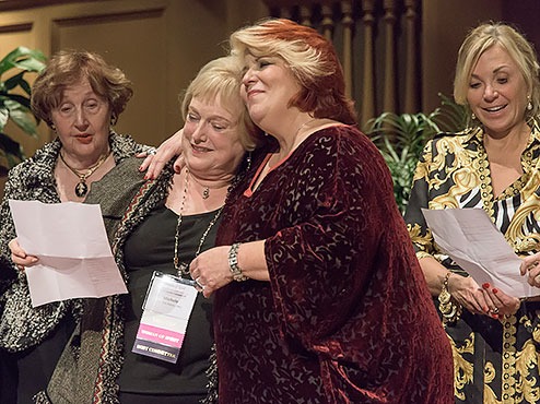 Four women relax at the Women of Spirit awards celebration with two of them embracing.