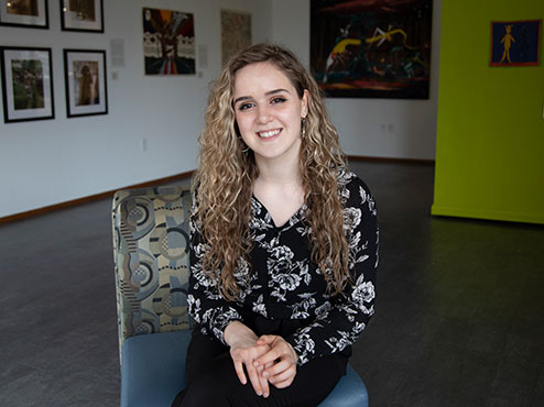 College student sitting in the art gallery, smiling.