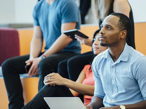 Students at a graduate admissions event are focused on the presentation.