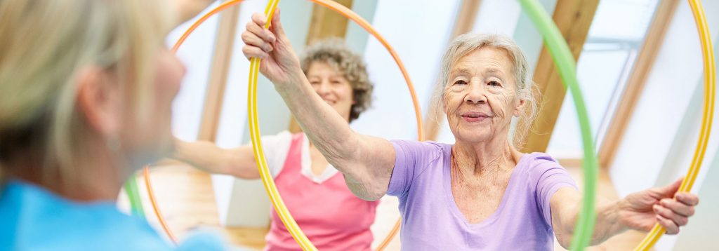 Seniors do fitness training with the tire in the physiotherapy