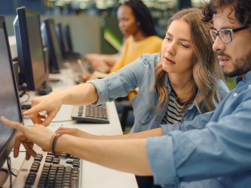 Information Technology: Two community health students working together in front of a computer.