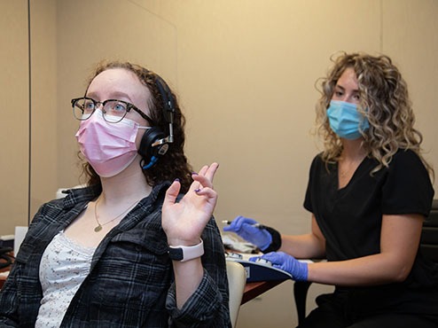 A speech-language pathologist administers a hearing exam to a patient at Carlow's SLP clinic.