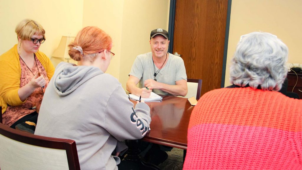 Group of MFA students sitting around a table discussing ideas