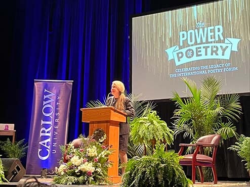 Naomi at the podium on the stage at the Power of Poetry event.