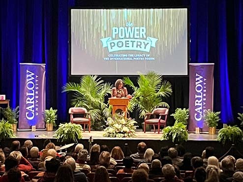 Tracey Smith at the podium on the stage at the Power of Poetry event.