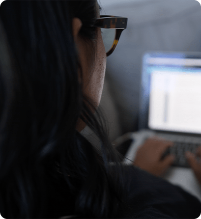 A student wearing glasses works on a laptop