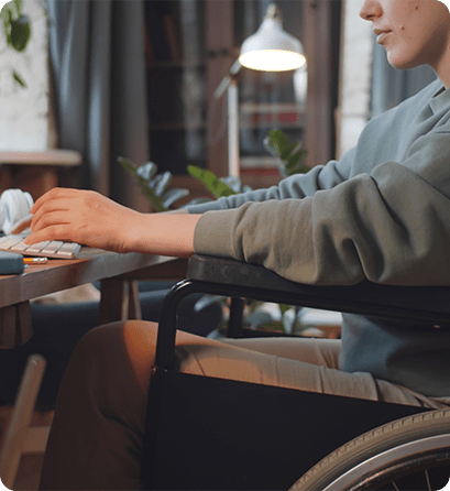 A student using a wheelchair works at a desk with a keyboard