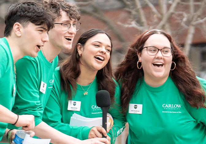 Carlow University students in green Carlow shirts laughing during an interview