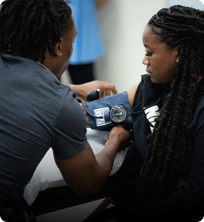 A Carlow nursing student taking a classmate's blood pressure